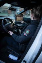 Police officer checking computer screen